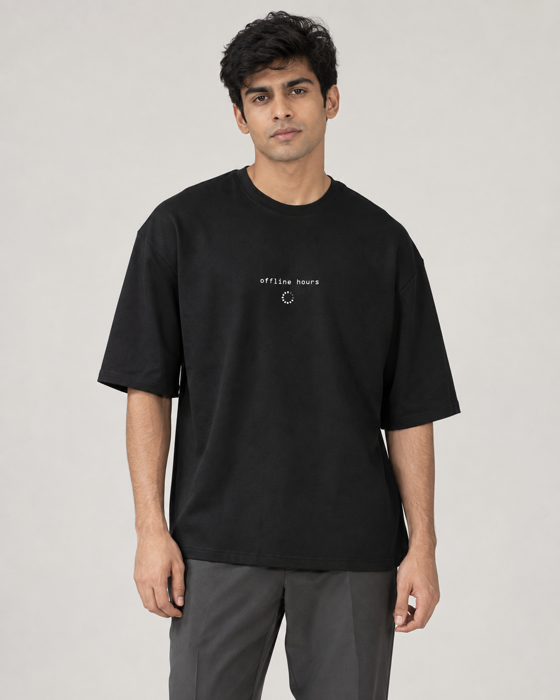 Model wearing a black oversized Toxikiing t-shirt with a small centred chest print reading 'offline hours' in monospace lowercase above a dotted loading-spinner circle