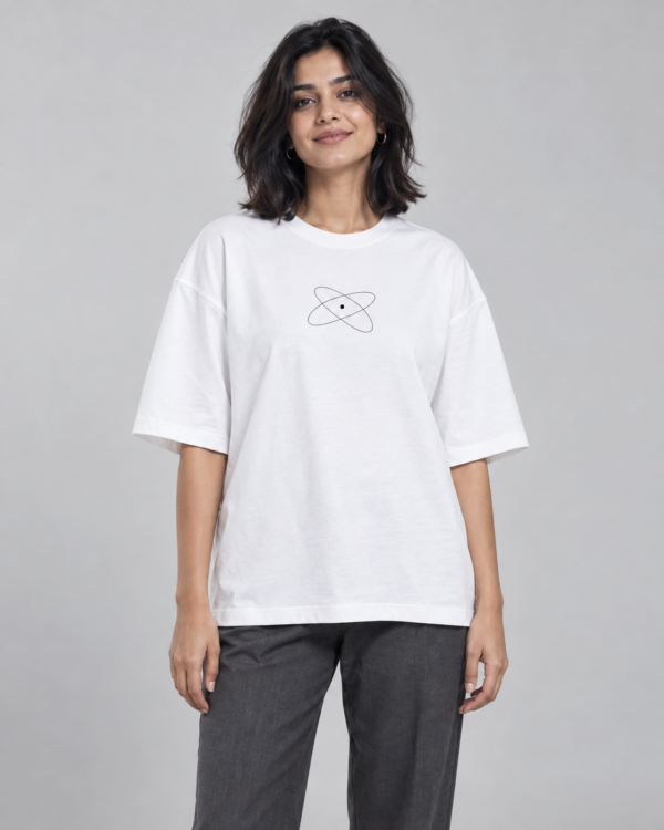 Model wearing a white oversized Toxikiing t-shirt with a small centred line-art chest print of two intersecting orbital ellipses around a solid dot